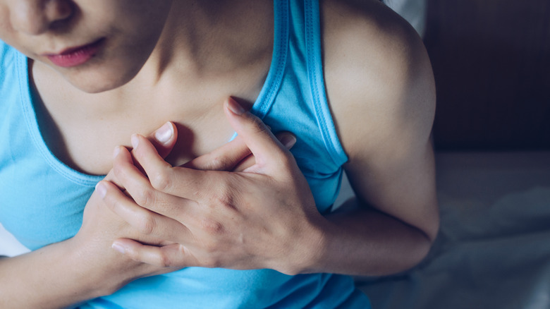 young woman holding onto chest in discomfort