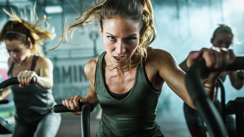 three women putting in hard workout on stationary bike