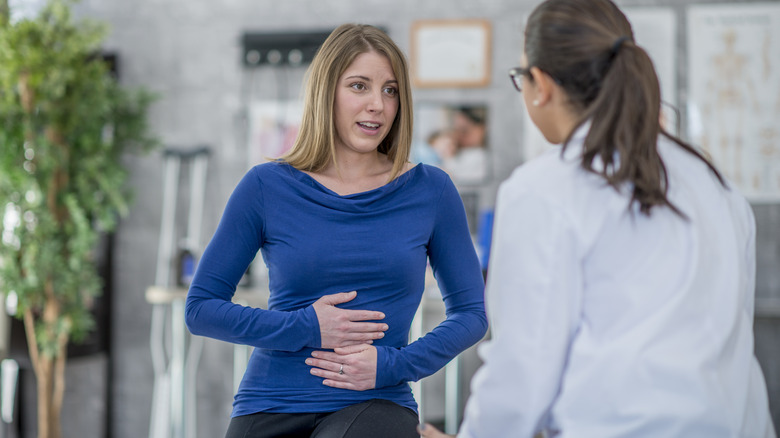 Woman with upset stomach talking to doctor