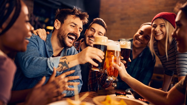 group of friends toasting alcoholic drinks in a bar