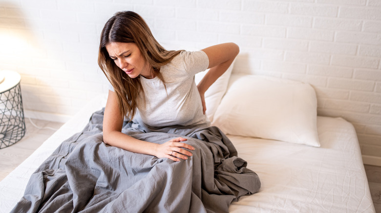 woman sitting in bed with back pain