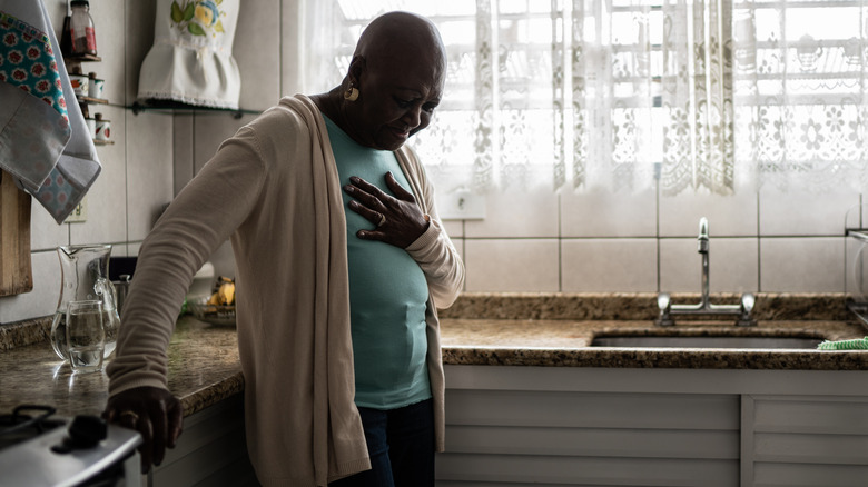 Wincing woman holding chest in pain