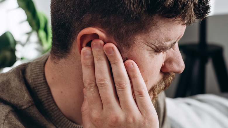 Pained man holding cartilage of ear