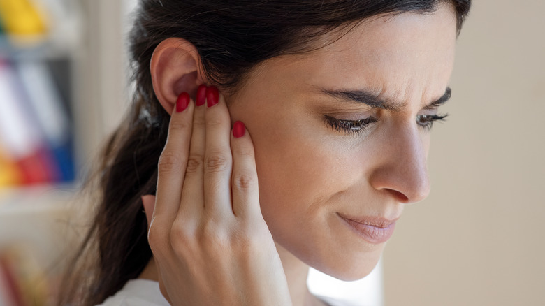 unhappy woman holding ear in discomfort