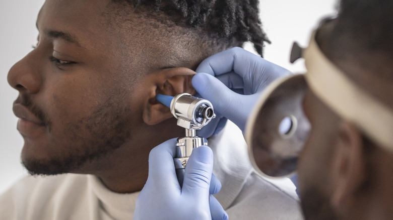 Doctor examining young man's ears