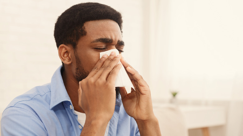 Man blowing nose in tissue