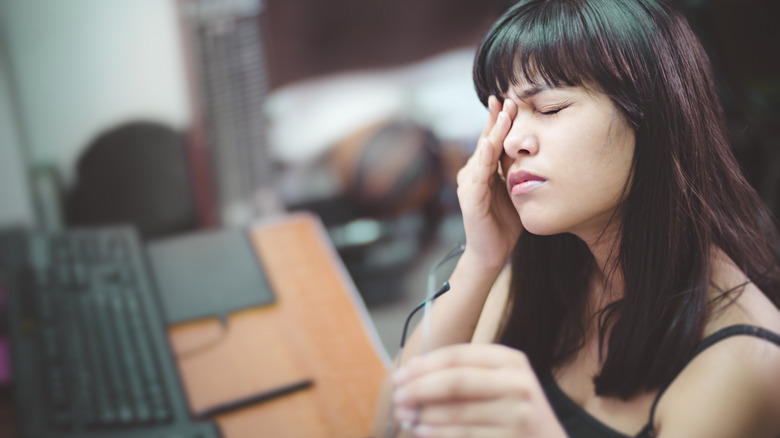 person sitting at computer rubbing their eyes