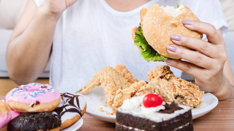 woman eating fried chicken and donuts