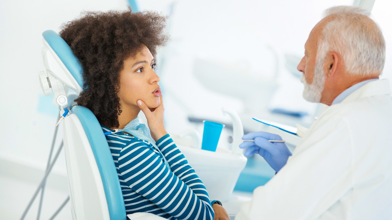Woman holding her jaw at dentist