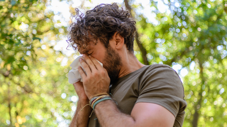 Man sneezing with allergies outdoors