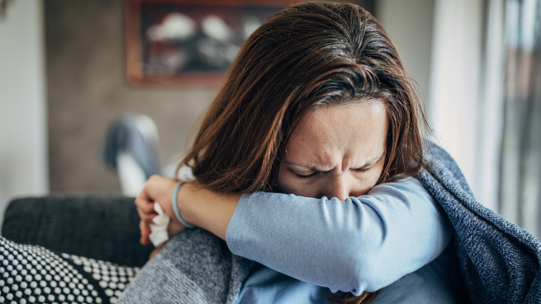 Woman sneezing into arm