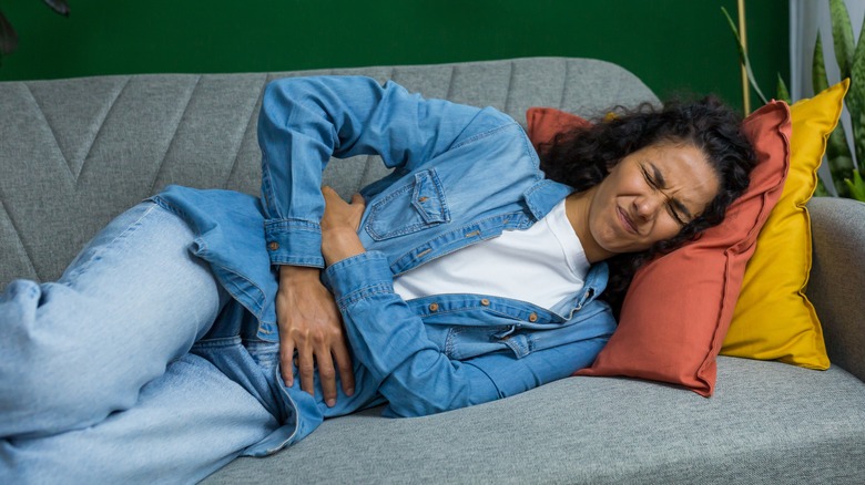 Woman in pain laying on couch