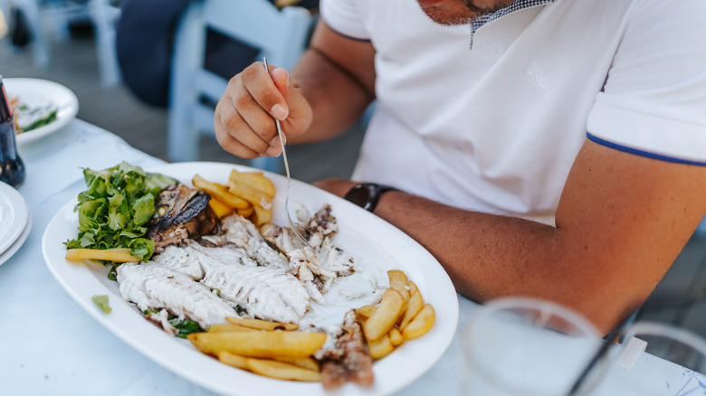 Man eating plate of fish