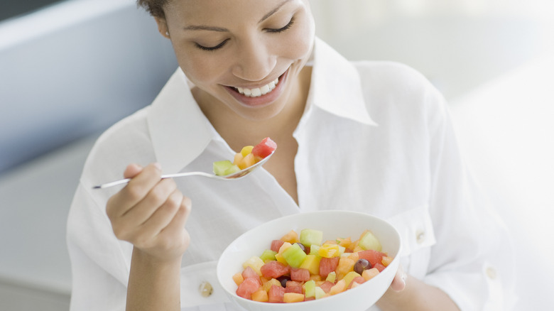 Woman eating bowl of fruit