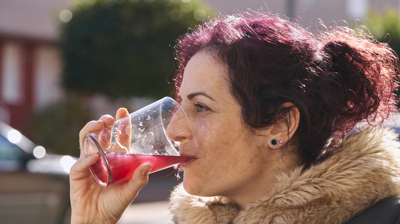 woman drinking cranberry juice outdoors