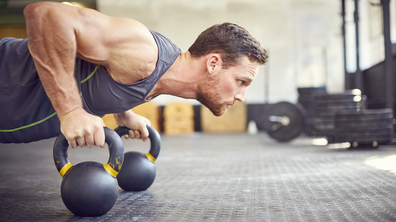 man doing push-ups with kettlebells