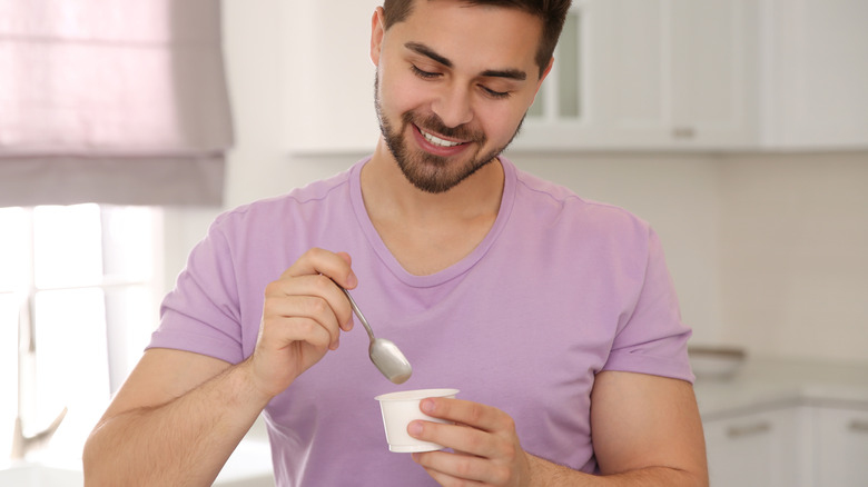 man eating yogurt in the kitchen