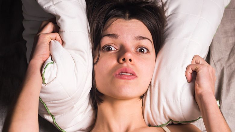 Woman clutching her pillow looking anxious