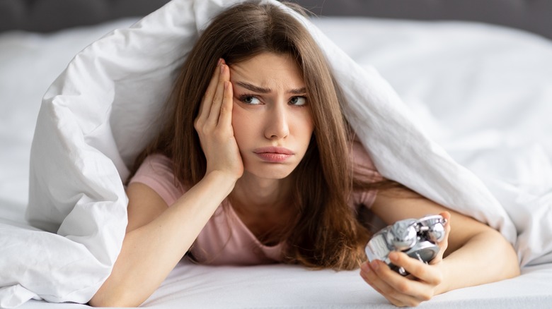 Woman looking disappointed under comforter