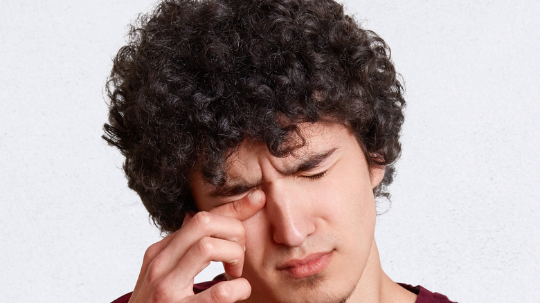 Young man rubbing his eye