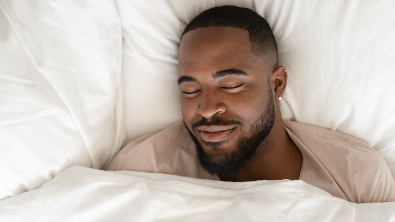 Man grinning with head on pillow
