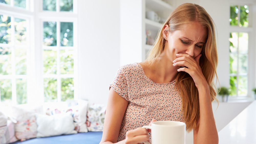 Woman cringing at taste of drink