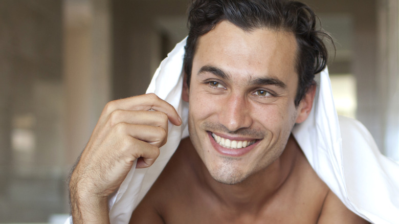 smiling man on bed under sheets