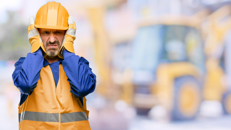 Worker holding hands over ears