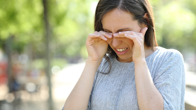 Woman rubbing eyes while wincing