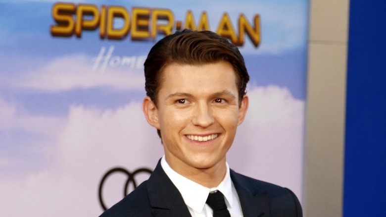 Tom Holland in front of Spiderman poster