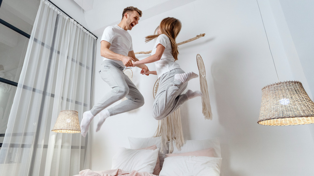 Happy couple jumping on bed