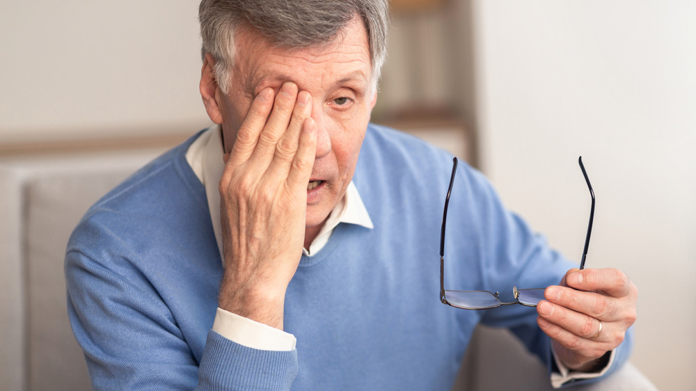 Older man taking off eyeglasses and rubbing eye