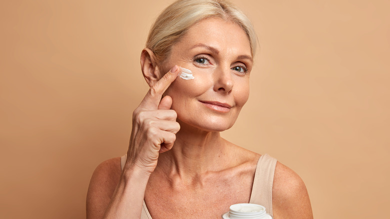 An older woman applying face cream, taking care of her skin 