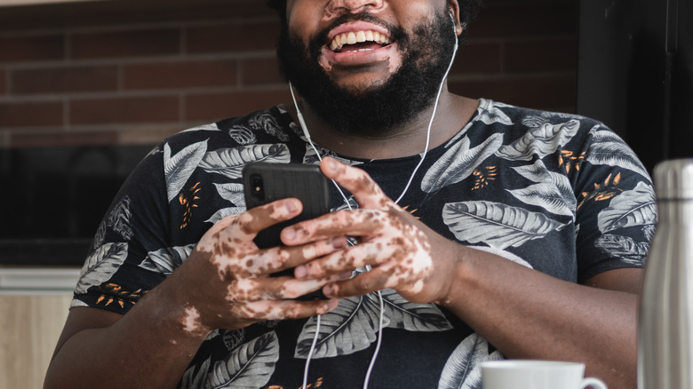 Smiling man with vitiligo listening to music