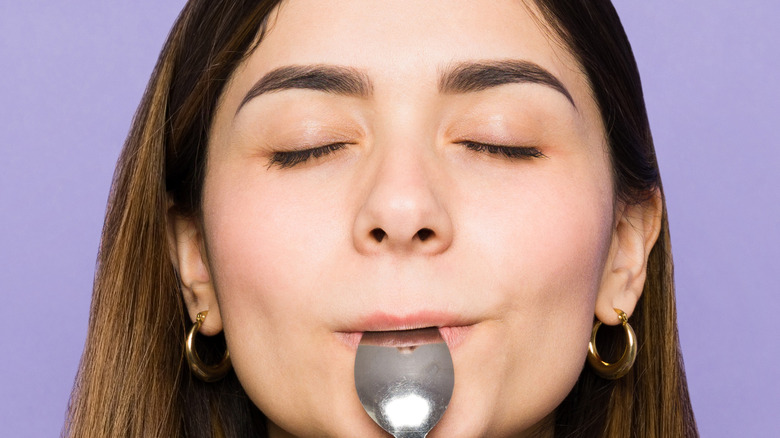 Woman holding a tablespoon and thinking about food