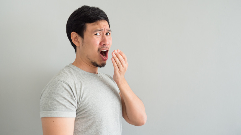 young man checking his own breath 