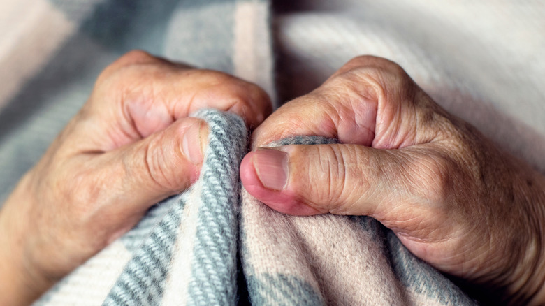 Cold hands clutching blanket