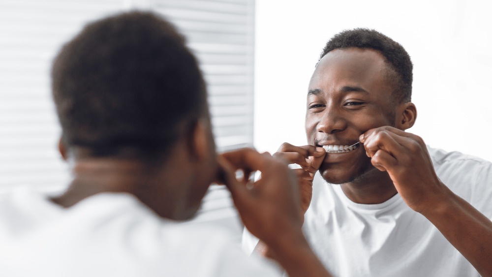 Man looking in mirror flossing