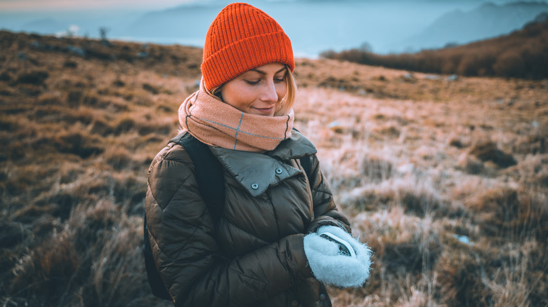 A woman wraps her hands around a hand warmer. 