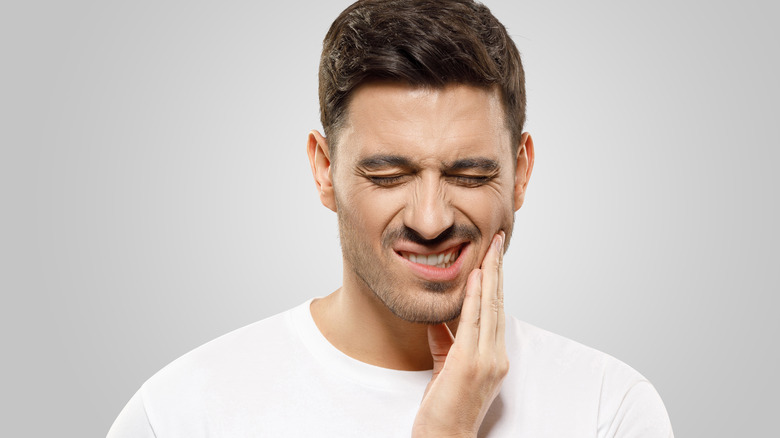 Man pressing fingers to jaw in pain