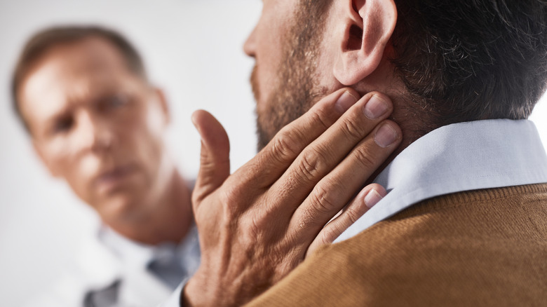 Doctor checking man's lymph nodes in neck