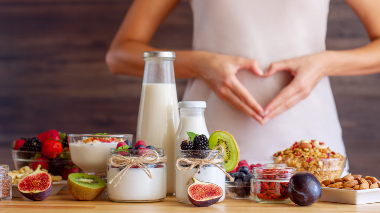 Stomach-healthy foods in front of woman with hands in shape of heart