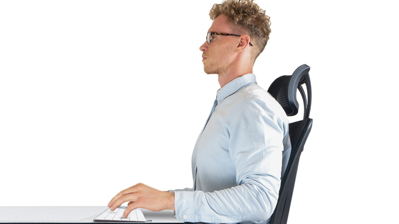 Male sitting on office chair at desk with good posture and support