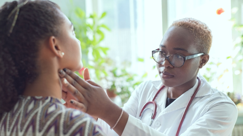 doctor examining patient's thyroid