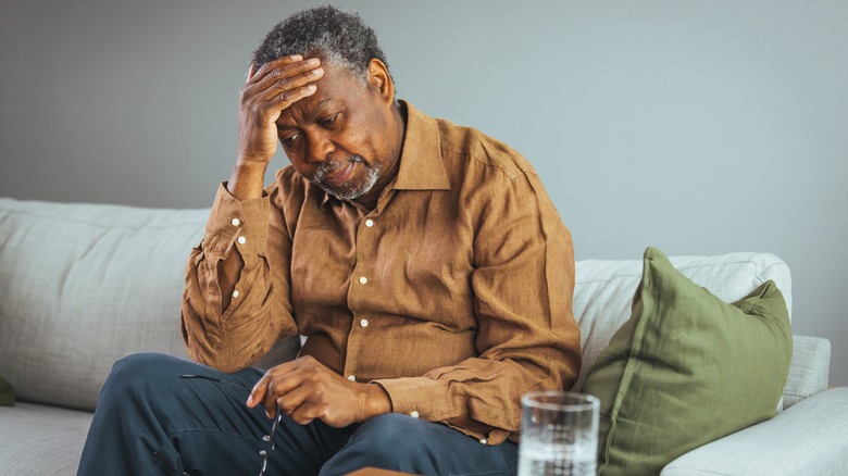 Man with chronic pain sits on couch