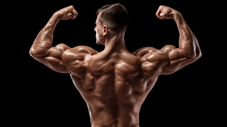 man flexes back and arm muscles 