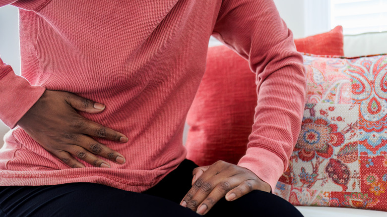 A woman's hand holding her abdomen in pain