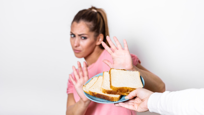 Woman holding hands up refusing a plate of bread