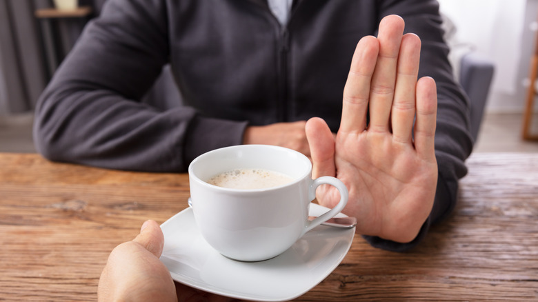 Close up of man holding up hand refusing coffee