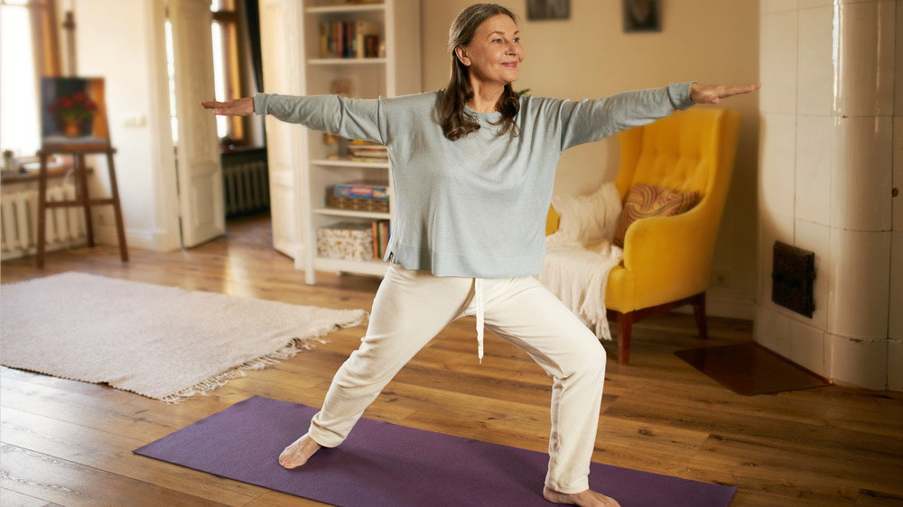 Older woman practicing yoga on mat in home